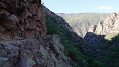 A-hiker-walking-along-the-trail-in-Caranca-Gorges-in-French-Pyrenees-during-summer-showcasing-steep-cliffs-and-beautiful-landscapes