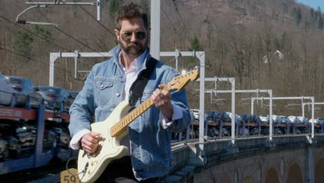 a moving train on a bridge behind a guitar player