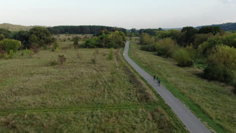 tres jóvenes andan en bicicleta en las hermosas llanuras de lituania, siguiendo la vista aérea