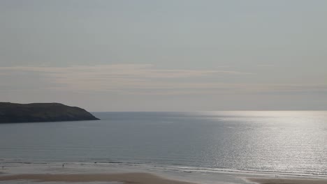 Wunderschöner-Woolacombe-Buchtstrand-Mit-Lundy-Insel-Hintergrund-Und-Heller-Sonne,-Die-Sich-Auf-Dem-Meer-Widerspiegelt