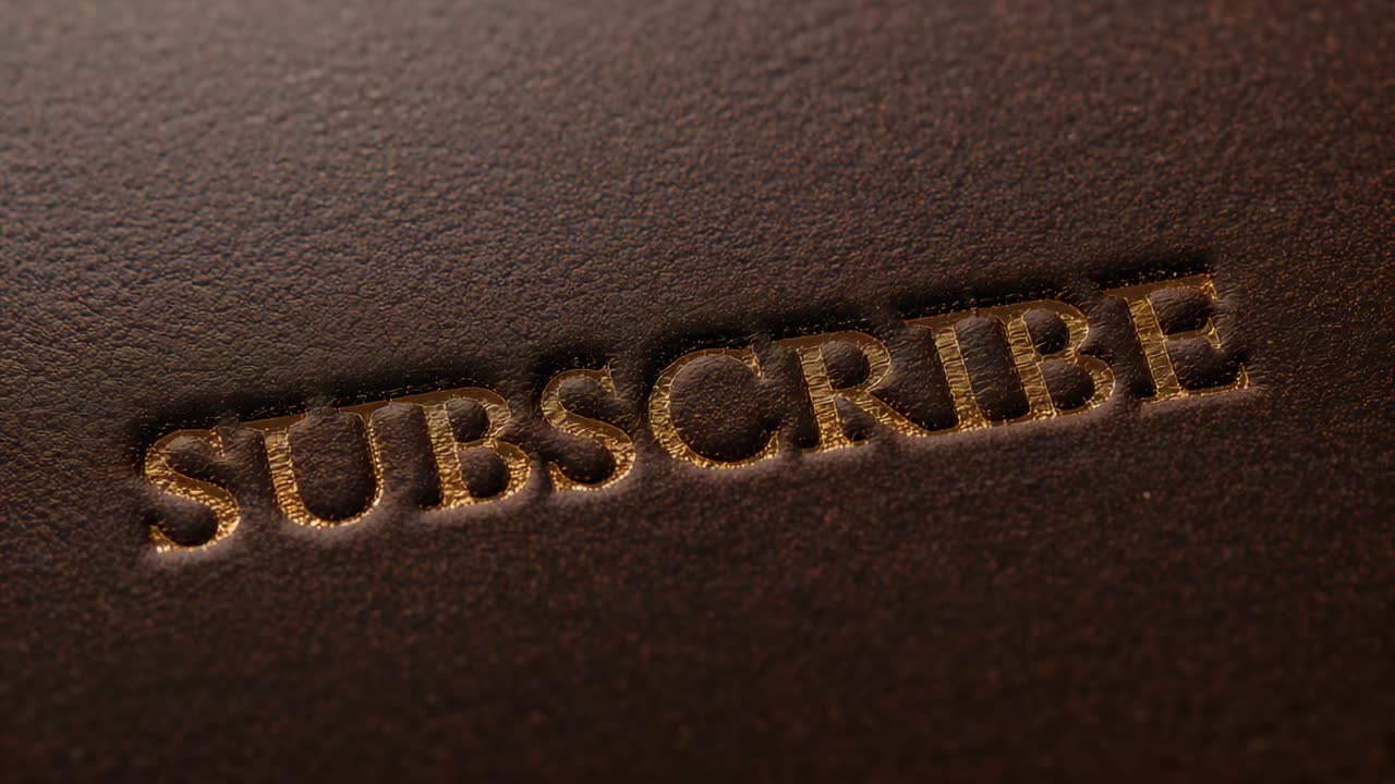Shifting camera and sweeping warm light focusing on debossed SUBSCRIBE in dark brown leather studio