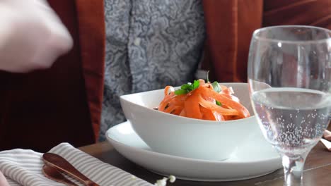 waitress serving pasta orange noodles at fine-dining restaurant. - closeup shot