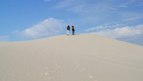 pareja con mochila caminando en el desierto en un día soleado 4k