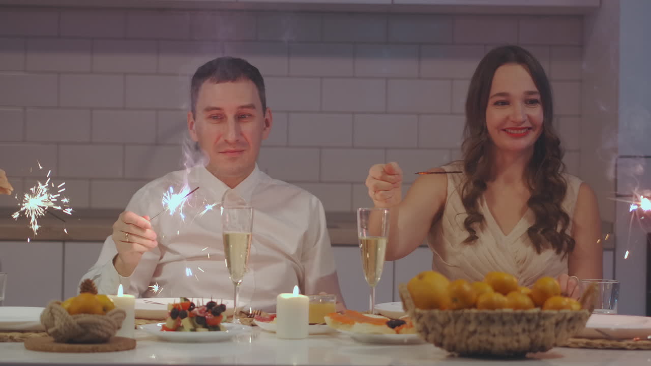 familia alegre con diferentes edades sosteniendo chispas celebrando la navidad. familia feliz. vacaciones de invierno. tradicional cena festiva de navidad en familia multigeneracional. disfrutando de la fiesta de la comida de navidad. imágenes de alta calidad 4k