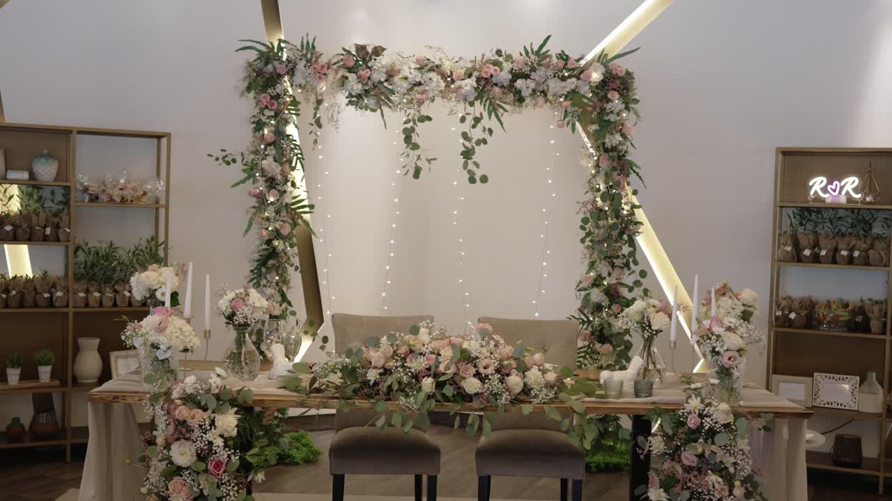 lavish wedding sweetheart table framed with flowers and lights in an indoor reception hall