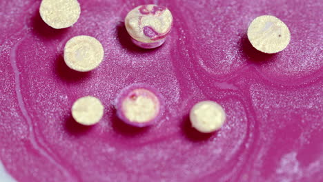primer plano de comprimidos efervescentes que se disuelven en una superficie rosada con burbujas y textura visibles