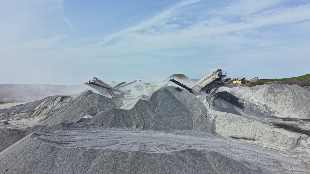 Cantera de granito con maquinaria en funcionamiento y pilas de piedra durante un día despejado