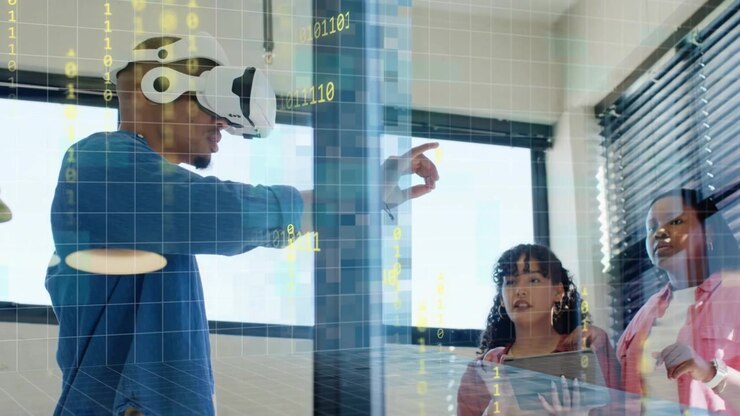 Uomo che indossa un visore VR, gesticolando e attivando una griglia di sovrapposizione tecnologica o binaria mentre il team usa un tablet per de