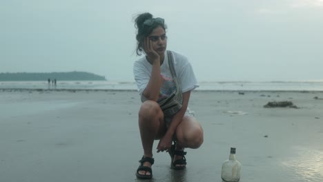 A-young-Asian-woman-crouches-on-the-beach-thinking-about-something-on-her-mind