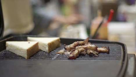 white bread placed onto barbecue grill with meat for charring toast, filmed as close up shot in slow motion handheld style