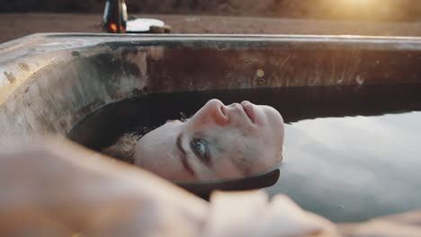 woman lying in dirty water in rusty bath in dystopian world