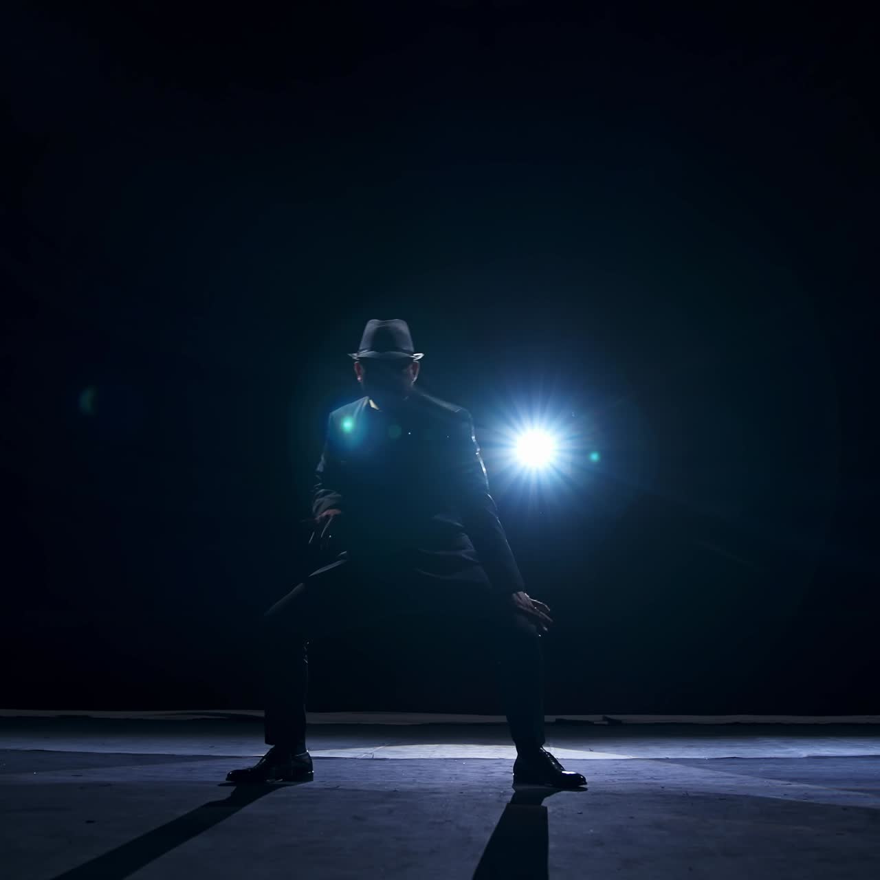 Silhouette of a man in classic hat and suit dances on a stage of classic theater. Dark light on stage. Concept video