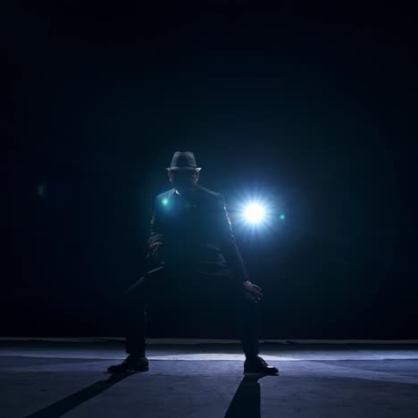 silhouette of a man in classic hat and suit dances on a stage of classic theater. dark light on stage. concept video