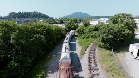aerial view of a freight train curving along the tracks near green hills and industrial areas in chattanooga, tennessee
