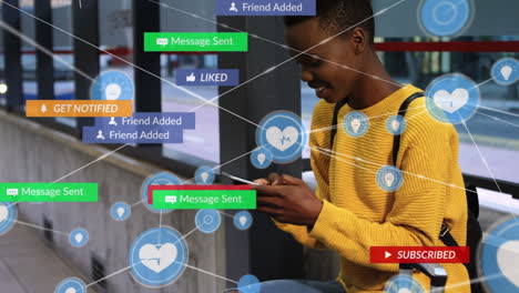 Animación-De-íconos-Digitales-Y-De-Redes-Sociales-Sobre-Una-Mujer-Afroamericana-Usando-Un-Teléfono-Inteligente-En-La-Parada-De-Autobús