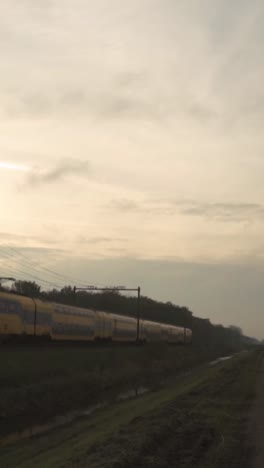 train passing through rural landscape at sunrise/sunset