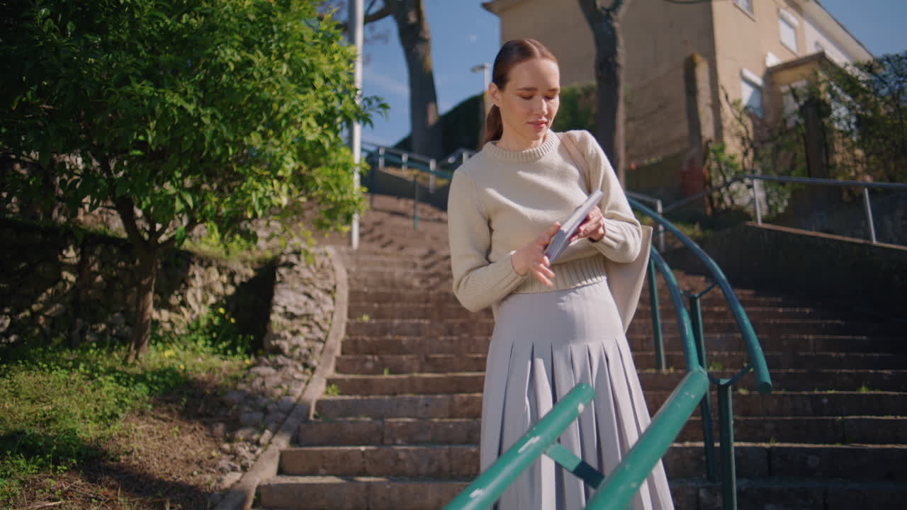 Happy teacher strolling staircase green trees nature. Romantic lady taking book