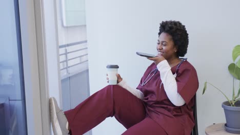 happy african american female doctor talking on smartphone in hospital, slow motion