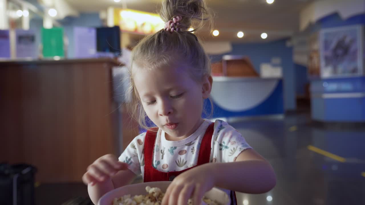 Bambina che mangia popcorn al cinema