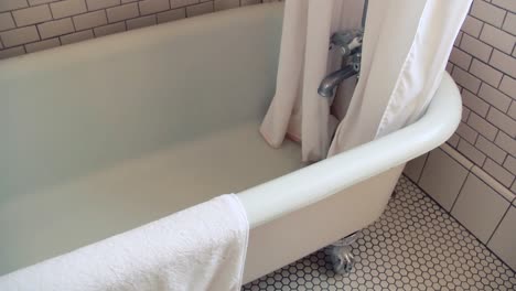 man turns faucet on in an old bathtub
