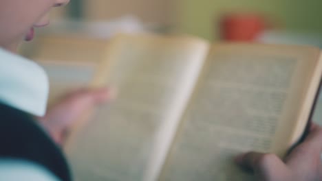 un escolar lee un libro en la mesa cerca de un amigo comiendo en la habitación