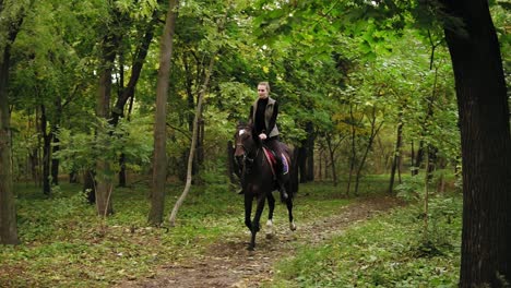 Young-female-rider-on-the-horse-on-a-shady-forest-gallop.-Allure-gallop.-Horseback-riding-on-a-sunny-day.-Horse-riding-in-the