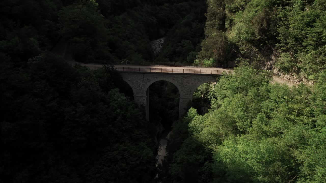 vista aérea hacia atrás de un puente en un valle rocoso
