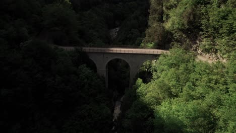 Vista-Aérea-Hacia-Atrás-De-Un-Puente-En-Un-Valle-Rocoso