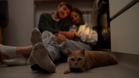 couple relaxing in the kitchen with their cat at night