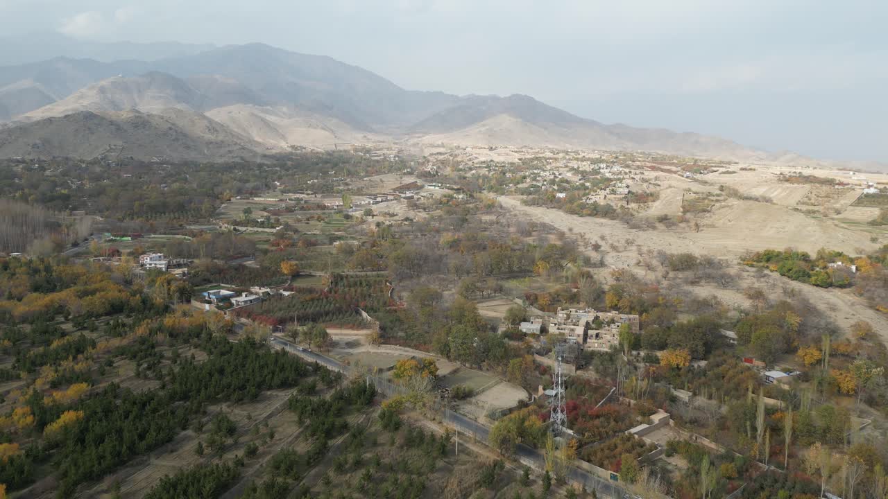 Aerial drone view of mountain villages and forest with golden autumn colors over Paghman region near Kabul, Afghanistan