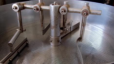 closeup of stainless steel drum style coffee roaster machine slowly turning after roasting a fresh batch of coffee beans