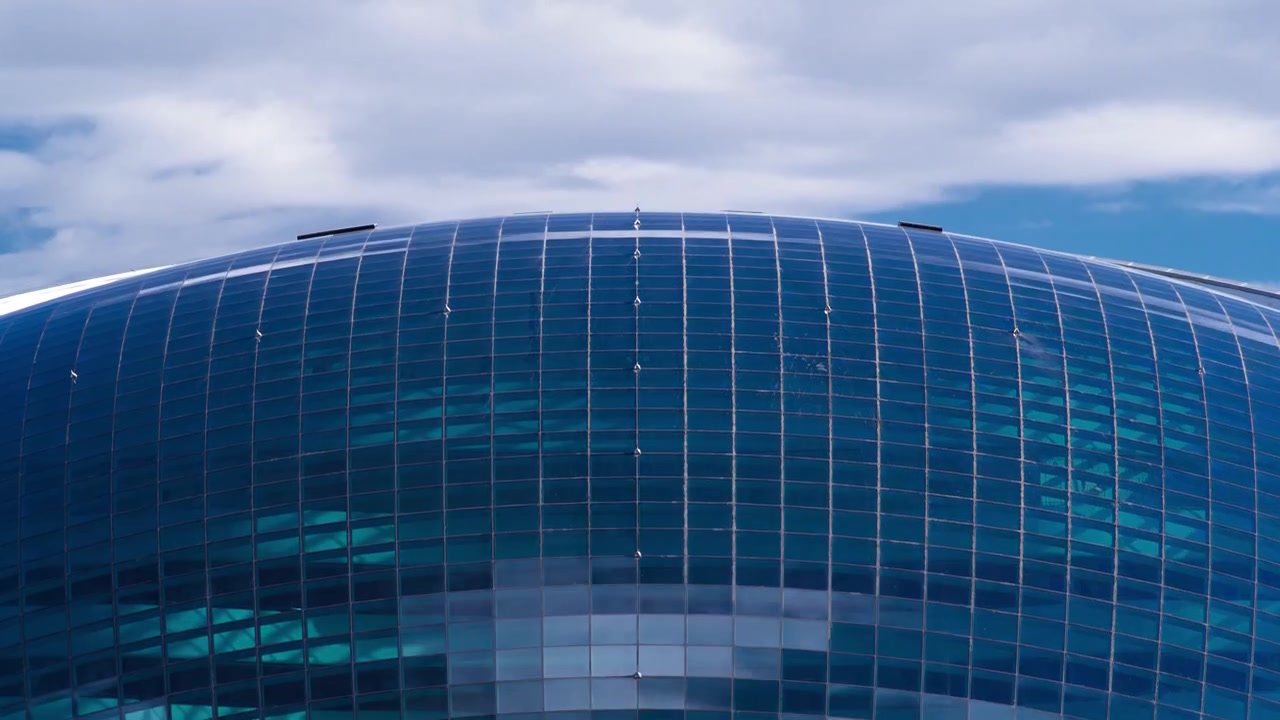 Centro Nazarbayev y torre azul, con nubes y reflejo en el cristal azul. Vista de cerca desde el puente. Cielo nublado. Astaná, Kazajistán.