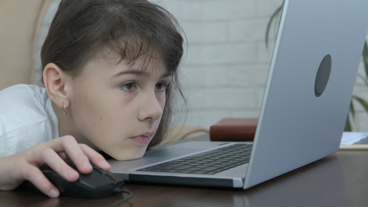 el adolescente mira hacia el monitor de la computadora portátil.