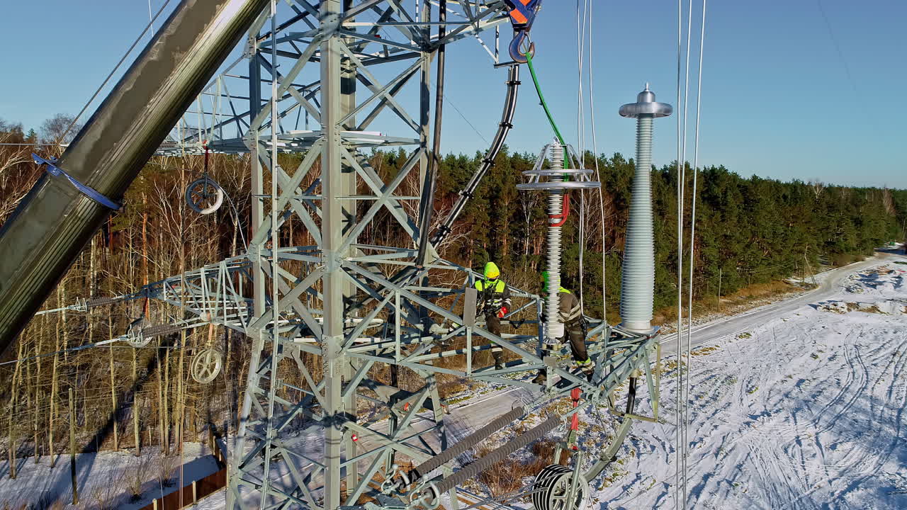 Two maintenance technicians sit high up on power lines maintenance work