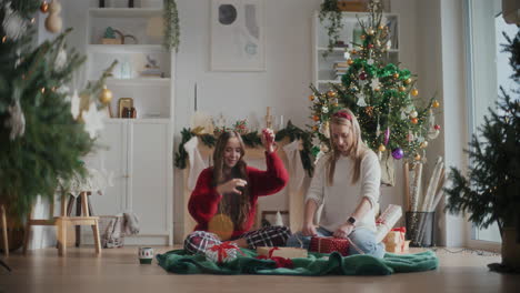 hermosas hermanas atando cintas en regalos de navidad envueltos en casa