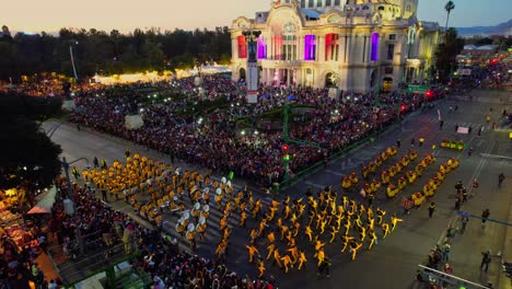 night parade with performers and large crowd in front of an illuminated grand building