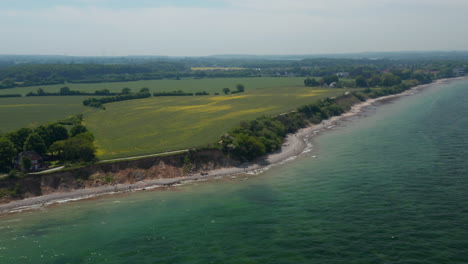 High-aerial-view-of-peaceful-coastline-scenery,-Baltic-sea-shoreline-in-Brodten,-Germany,-dolly-in,-day