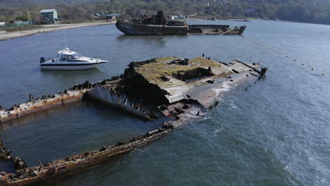 ships graveyard. two wooden derelict partially submerged shipwreck aground near the shore in the afternoon. aerial pivot  shot.