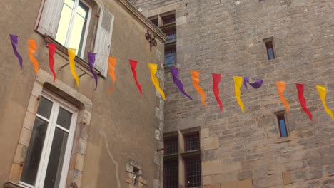 colorful festive bunting strung across buildings over street in guérande, france.
