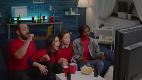 Multi-ethnic-friends-sitting-in-front-of-television-on-couch-while-watching-football