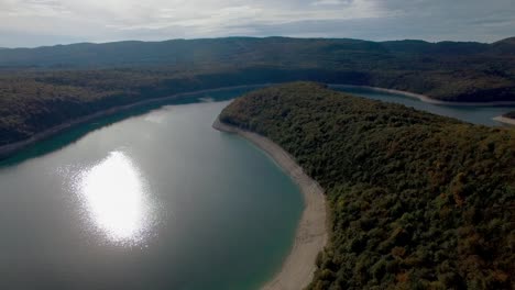 Toma-Aérea-Del-Lago-Lac-De-Vouglans-En-El-Río-Ain-En-Francia-Durante-La-Puesta-De-Sol