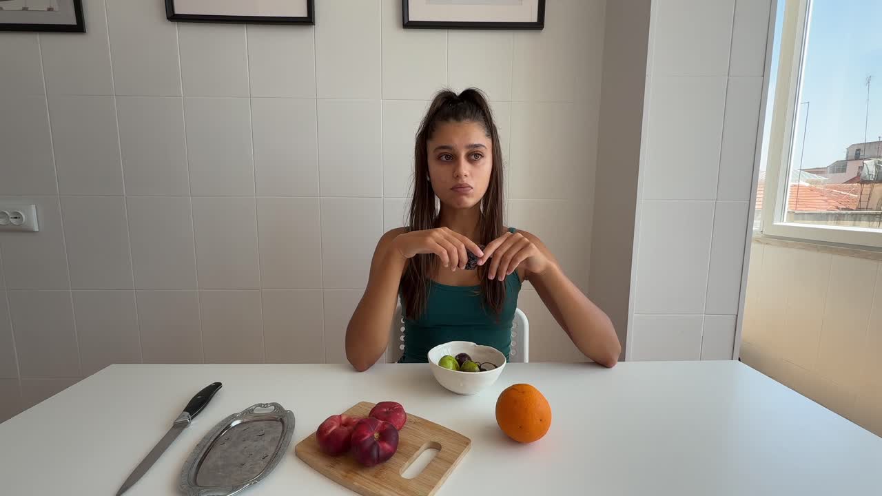 Young Woman Eating Fresh Grapes at a Kitchen Table
