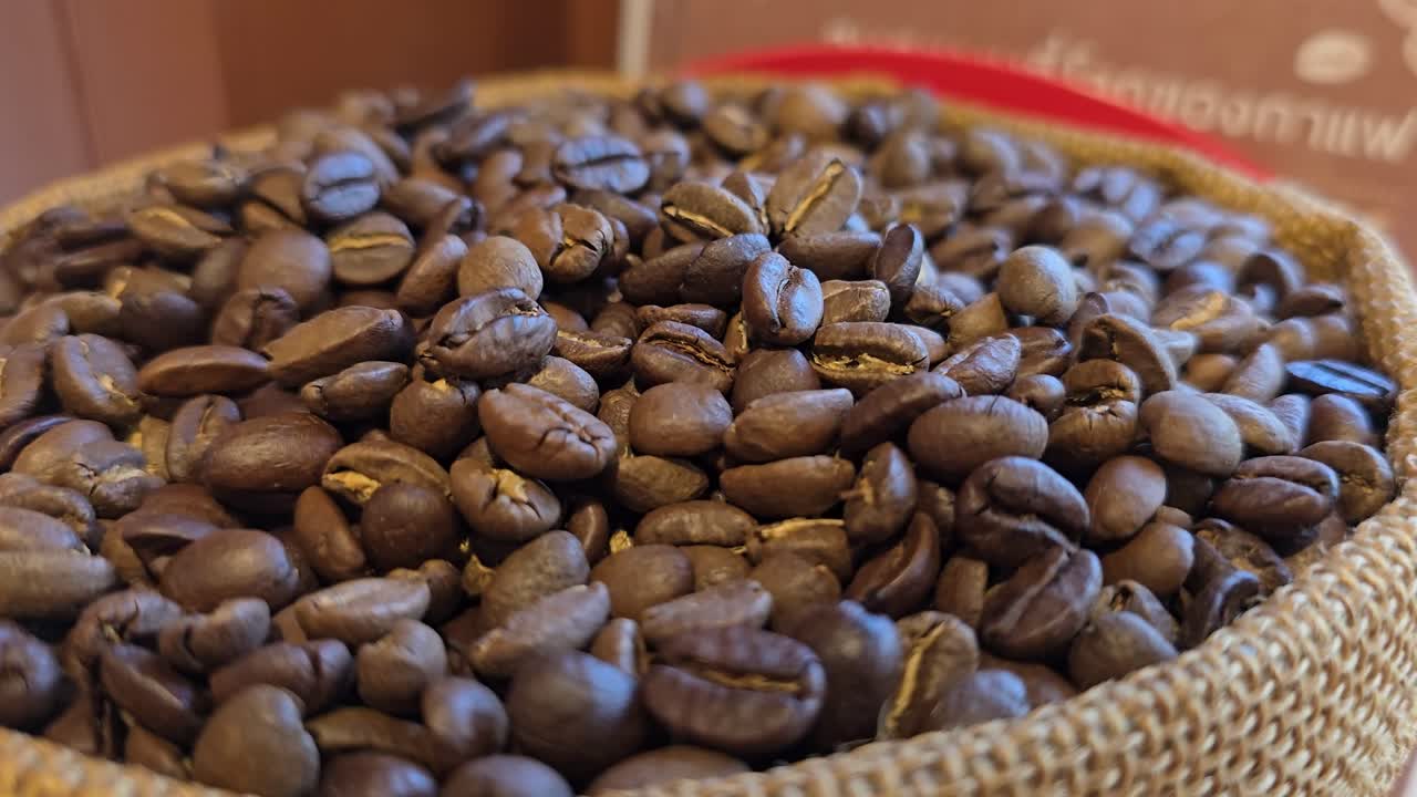 Primo piano, panoramica al rallentatore di chicchi di caffè marroni in una ciotola