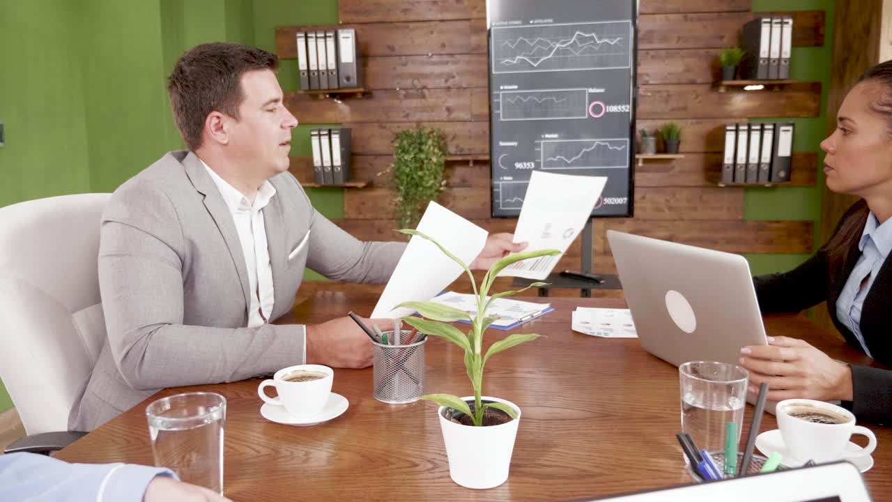 Businessman giving charts to his colleague in the conference room