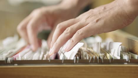 hands of a business man searching for documents in a filing cabinet at the office.