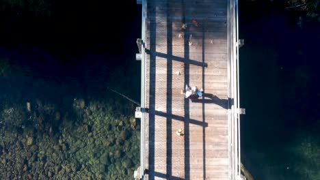 moving drone shot looking down at woman walking on trestle in british columbia canada