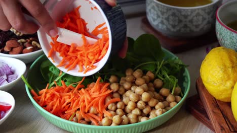 Toma-Manual-Haciendo-Una-Ensalada-Agregando-Zanahorias,-Tomates,-Espinacas,-Garbanzos,-Limones,-Cebollas,-Nueces,-Aderezo-A-La-Vista.