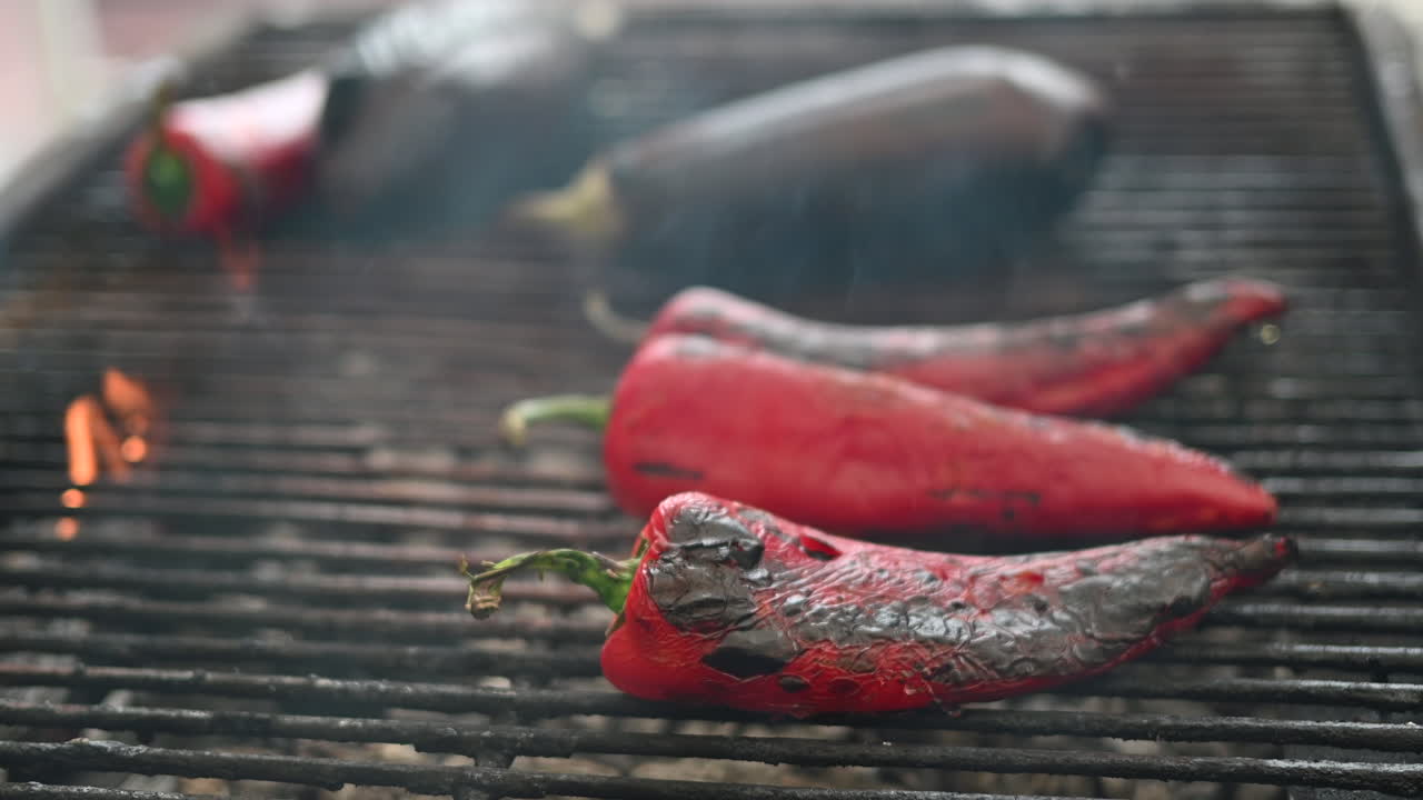 Red peppers and eggplants being prepared on a grill