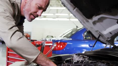 Mechanic-using-laptop-while-servicing-a-car-engine