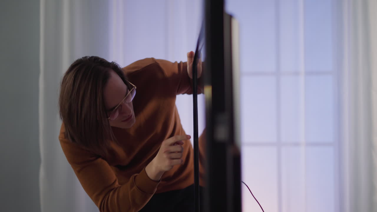 hombre joven con gafas sintoniza televisión inteligente contemporánea en casa